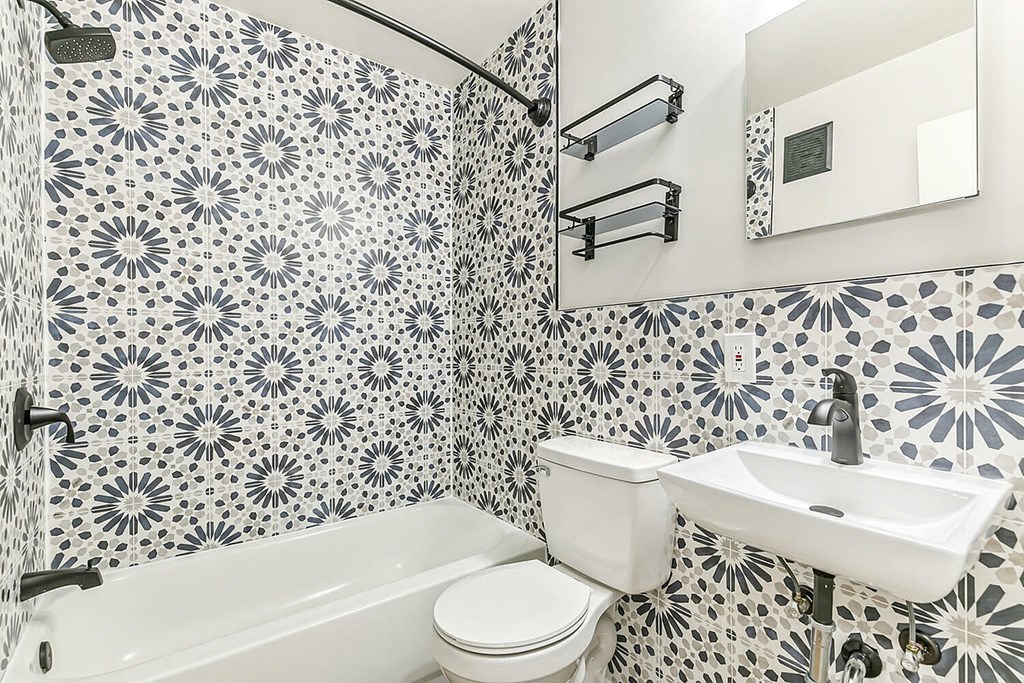 A white toilet sits next to a white sink in a bathroom with black and white tile.