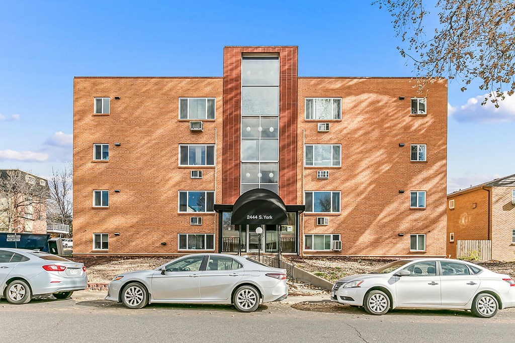 A modern brick building with cars parked in front.