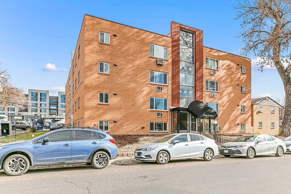 A blue car is parked in front of a brick building.