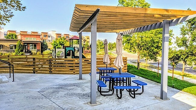 A picnic area with tables and chairs under a wooden canopy.