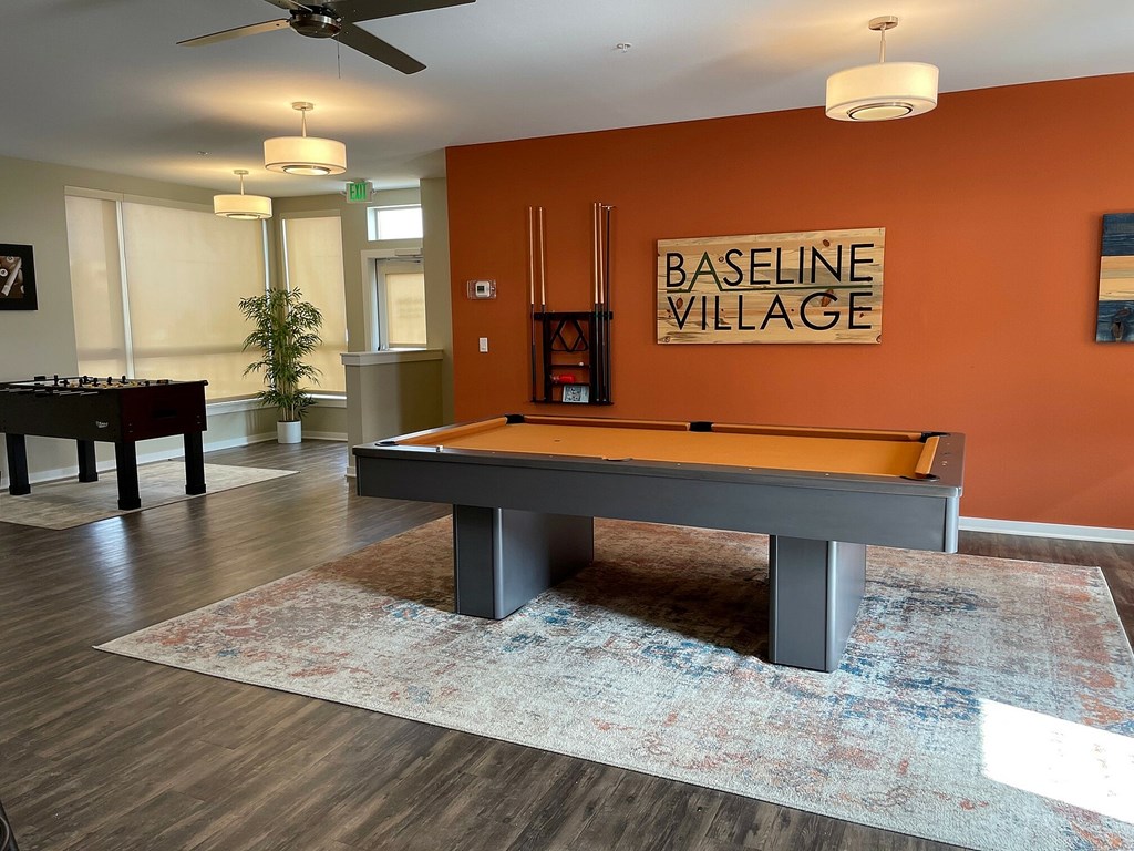 A Baseline Village billiard table sits in the middle of a room with a ceiling fan and lighting fixtures.