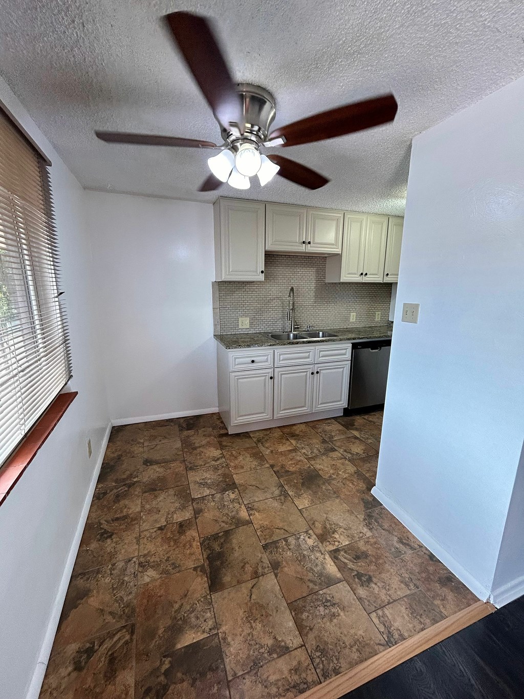 A kitchen with a fan and brown tiles.