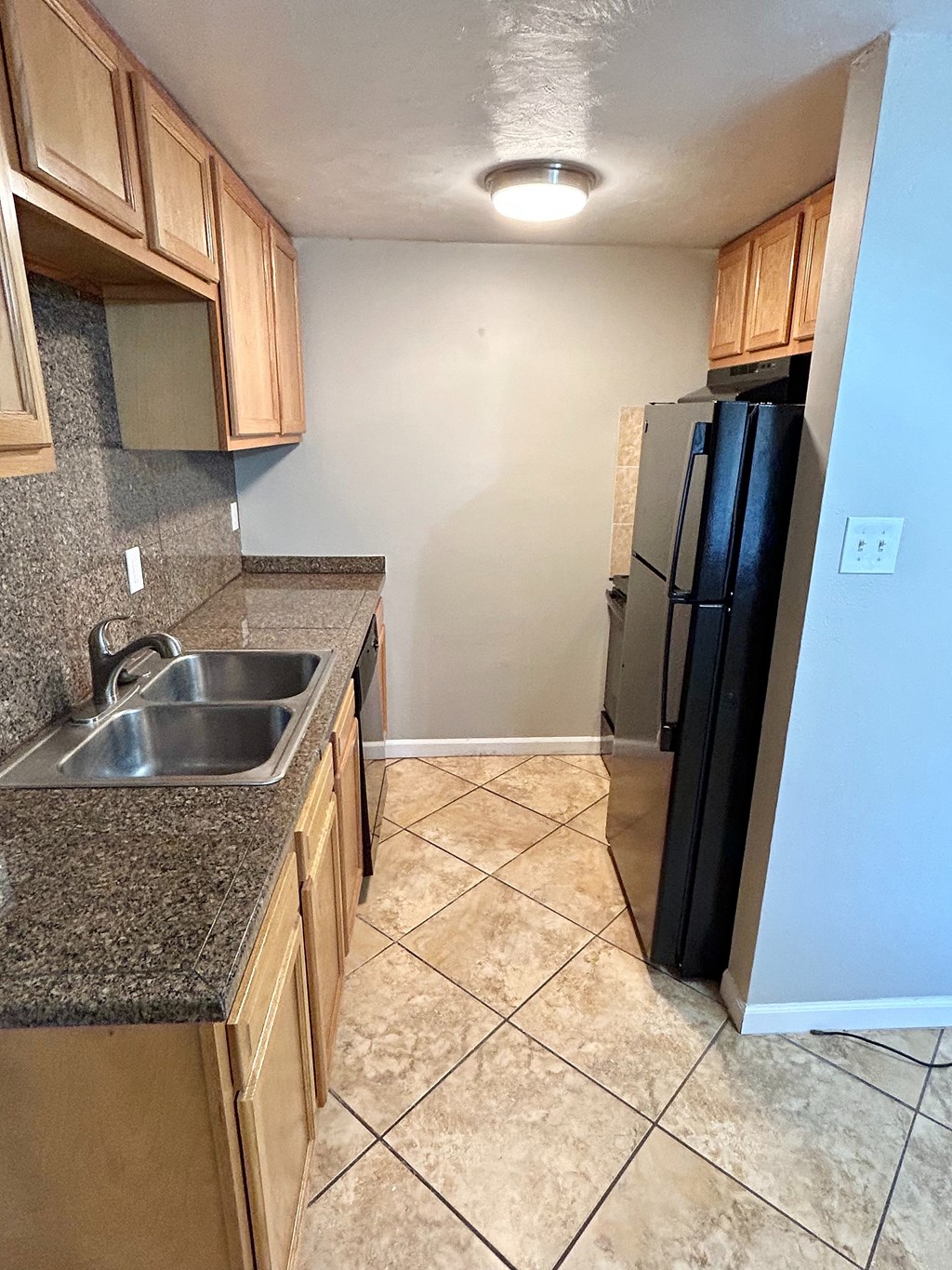 A kitchen with a black refrigerator and a granite counter top.