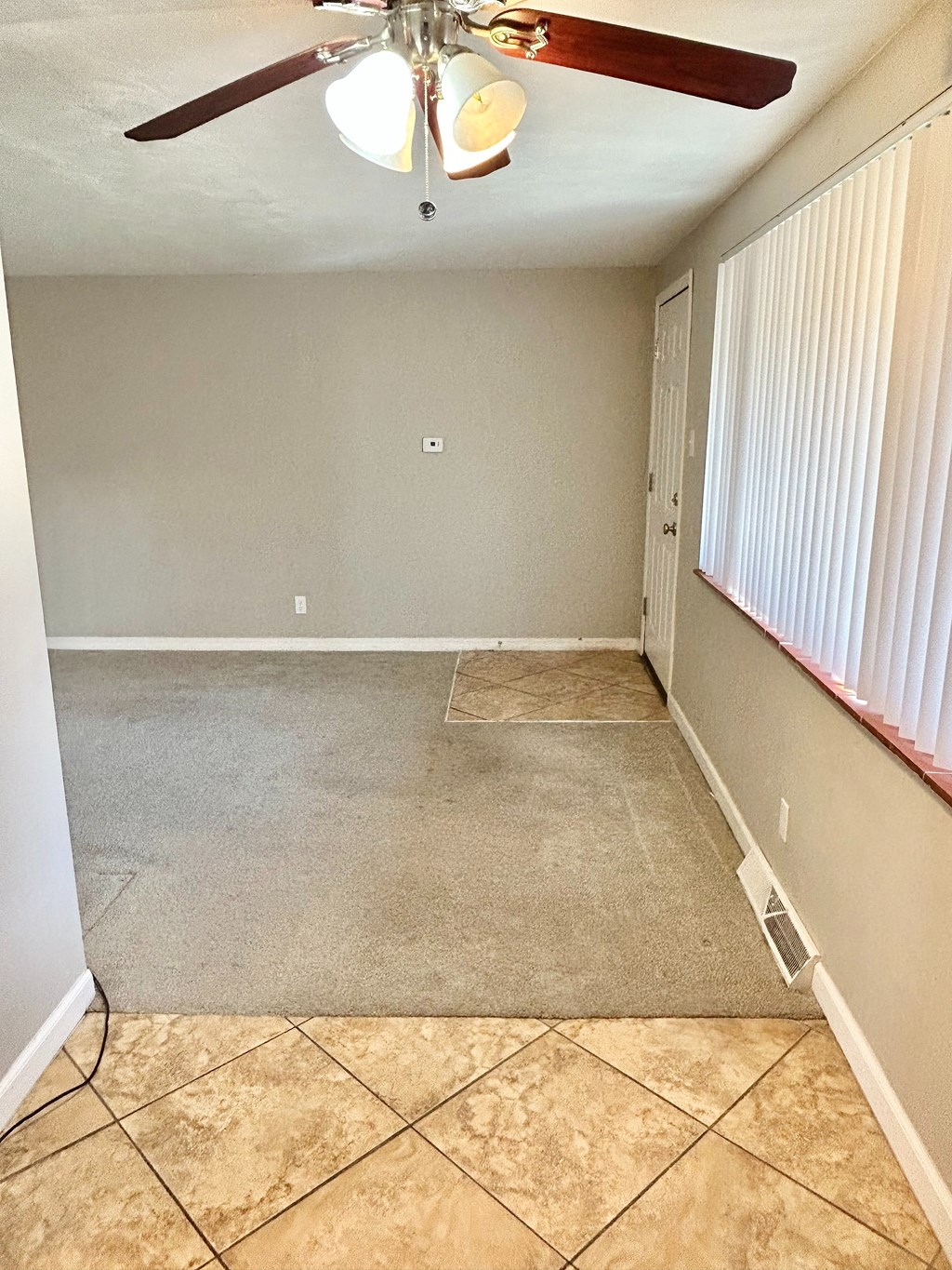 A room with a ceiling fan and tile flooring.