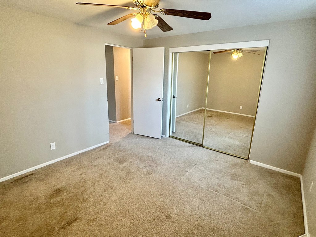 A room with a ceiling fan and a carpeted floor.