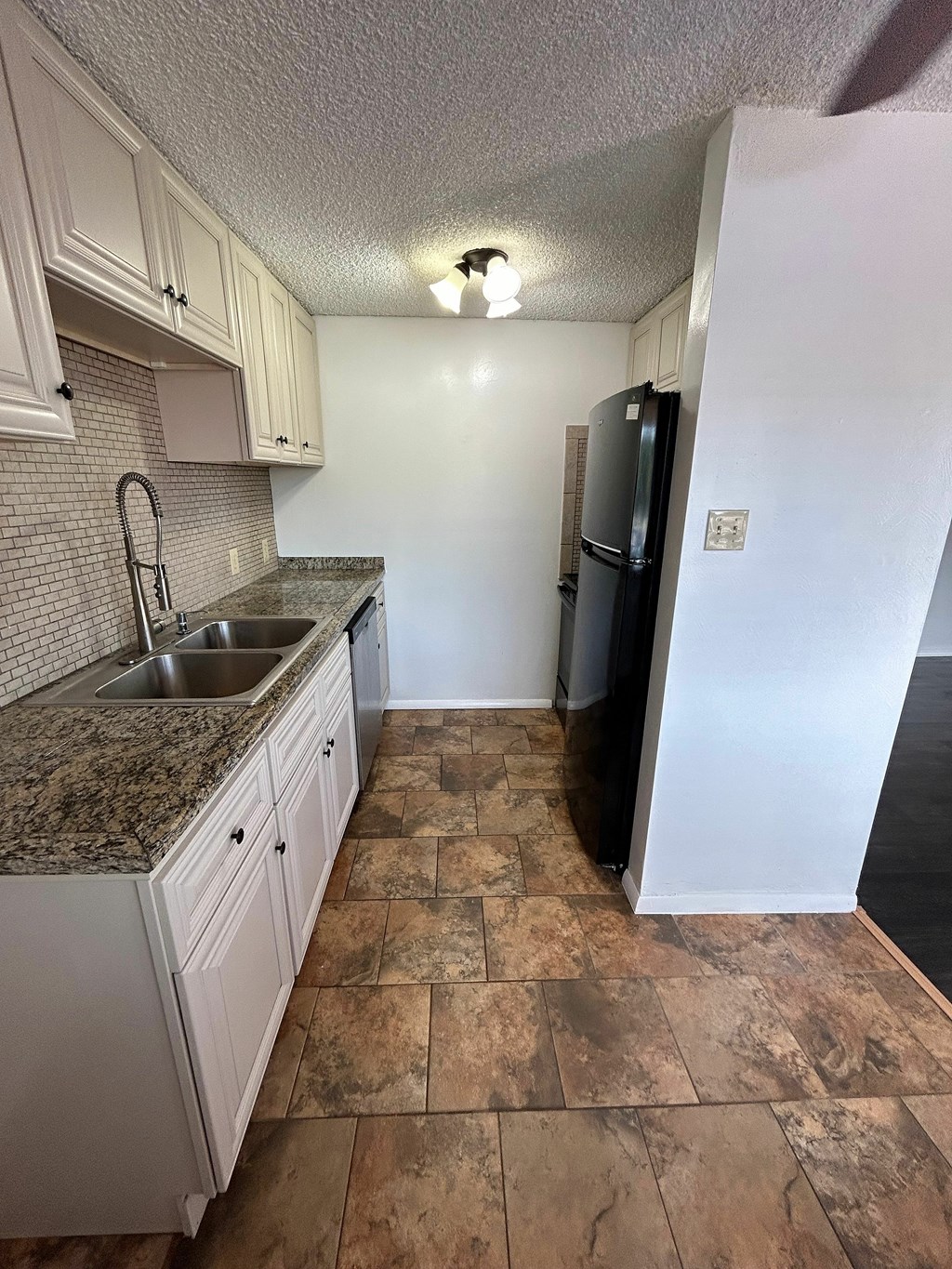 A kitchen with a black refrigerator and a sink.