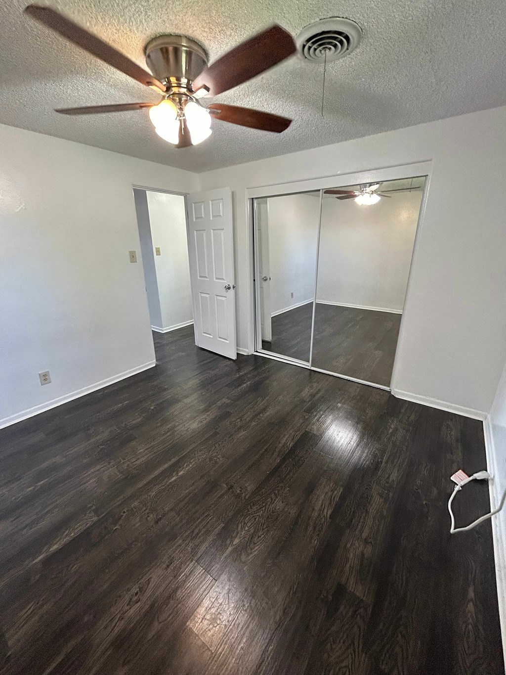 A room with a ceiling fan and wooden flooring.