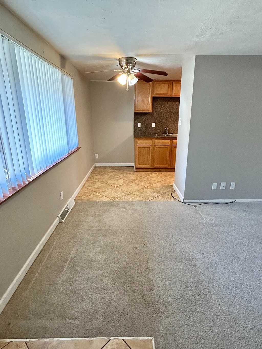 A room with a ceiling fan and a window with blinds.