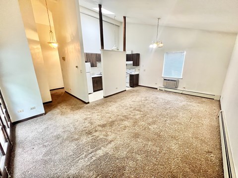 A carpeted room with a window and a desk.