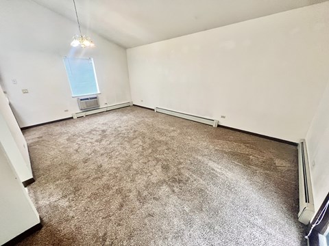 A room with a carpeted floor and a window with blinds.