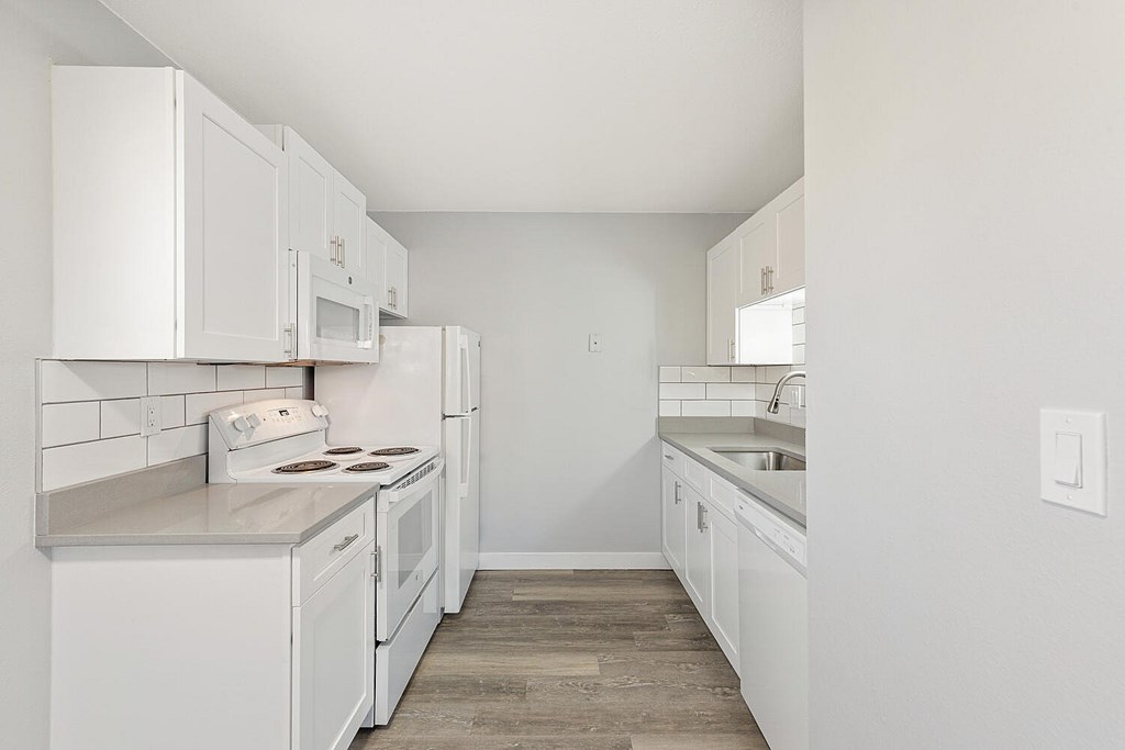 A kitchen with white cabinets and appliances.