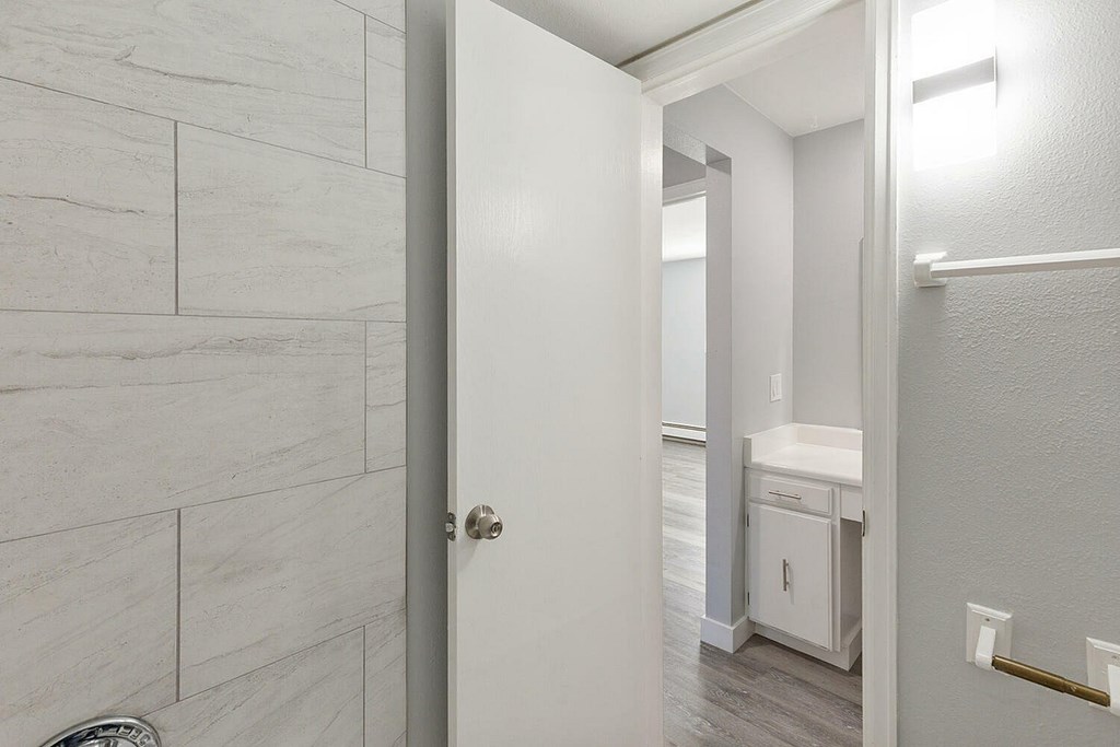 A white bathroom with a white door and a white sink.