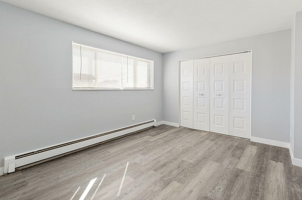 A room with a window and a door is empty and waiting to be furnished.