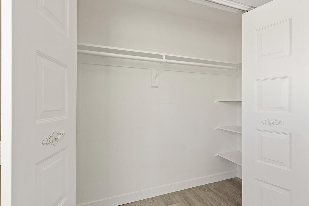A white door is open to a room with a shelf.