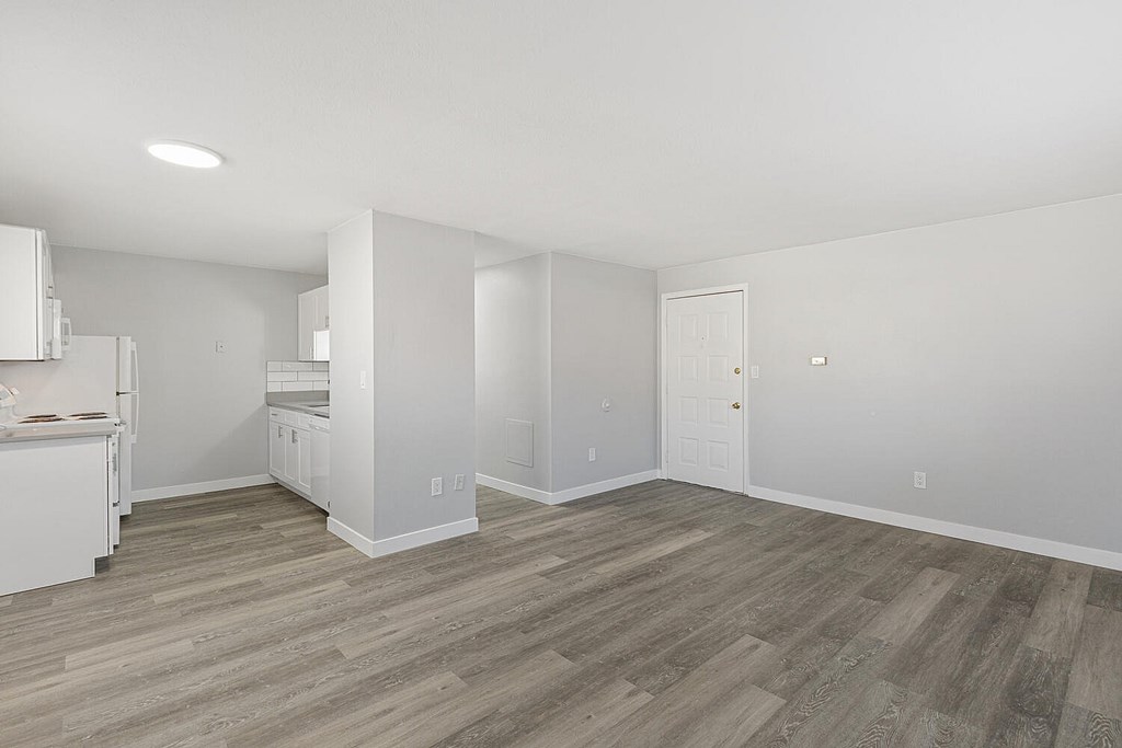 A kitchen with white appliances and a wooden floor.