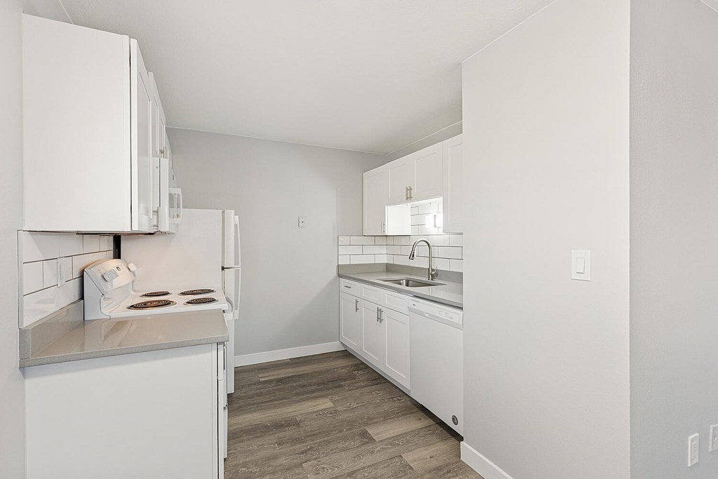 A kitchen with white cabinets and a white fridge.