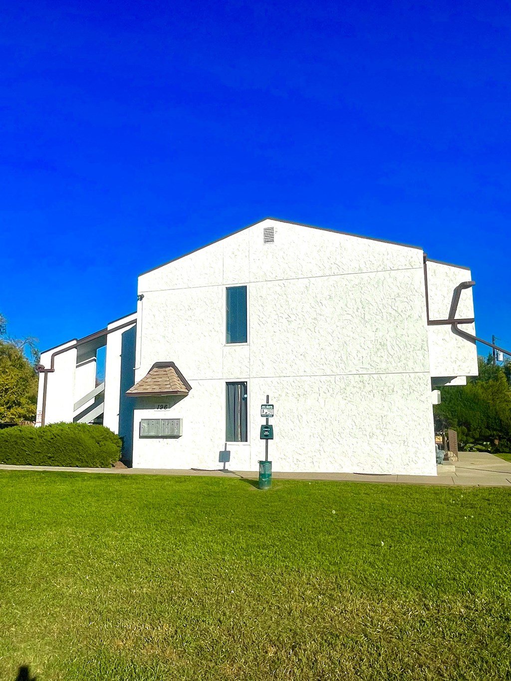 A white building with a green lawn in front.