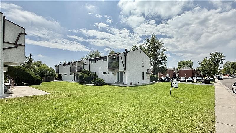 A grassy area in front of a building with a sign in the foreground.