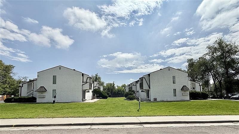 Two white houses with green lawns in front.