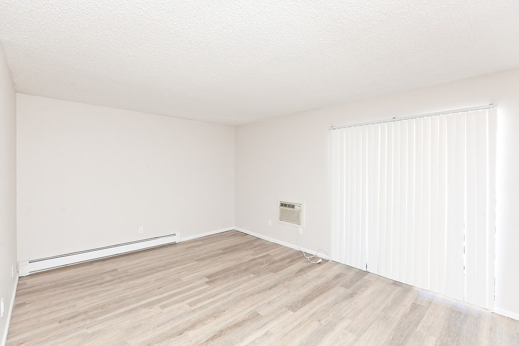 A room with wooden flooring and white walls.