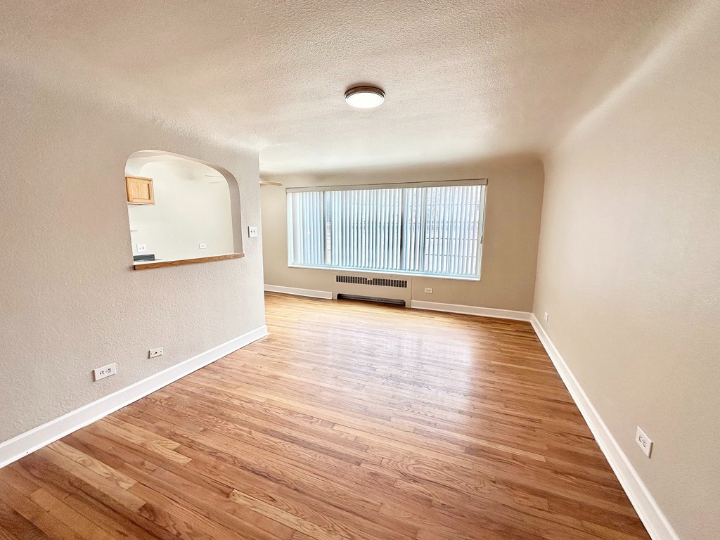 A room with wooden flooring and a window with blinds.