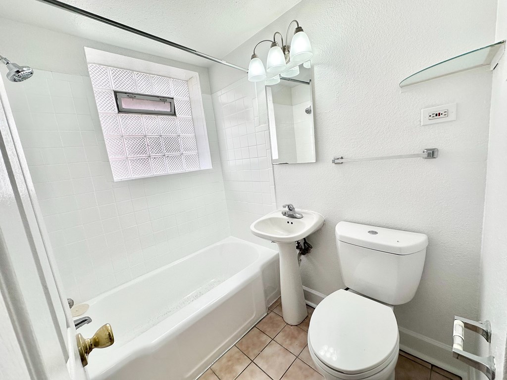 A white toilet sits next to a white sink in a small bathroom.