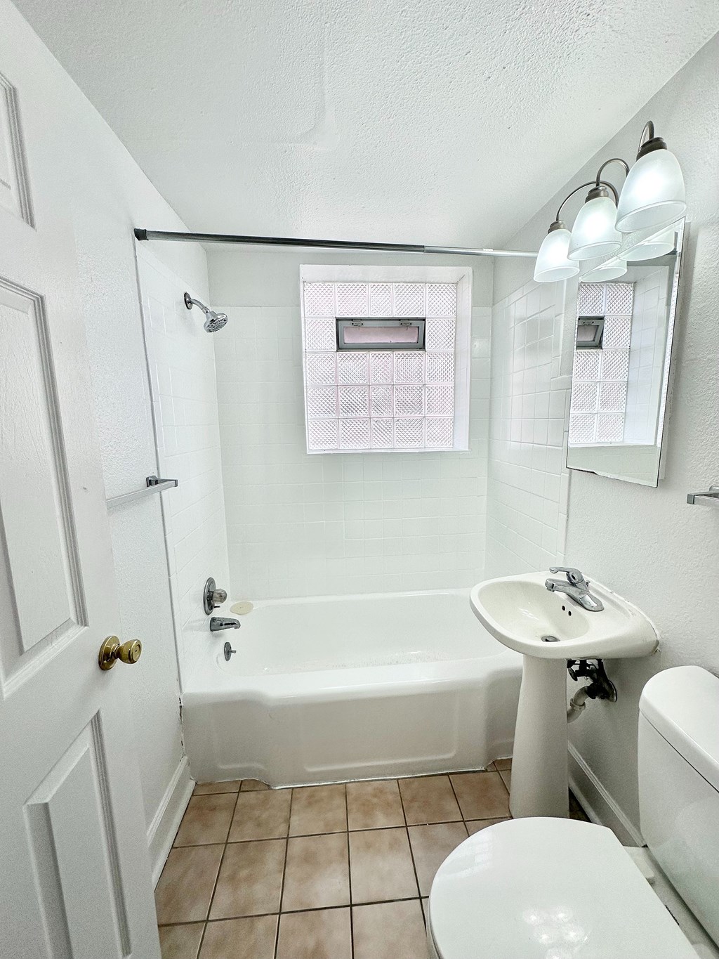 A white toilet is in a bathroom with a white tub and sink.