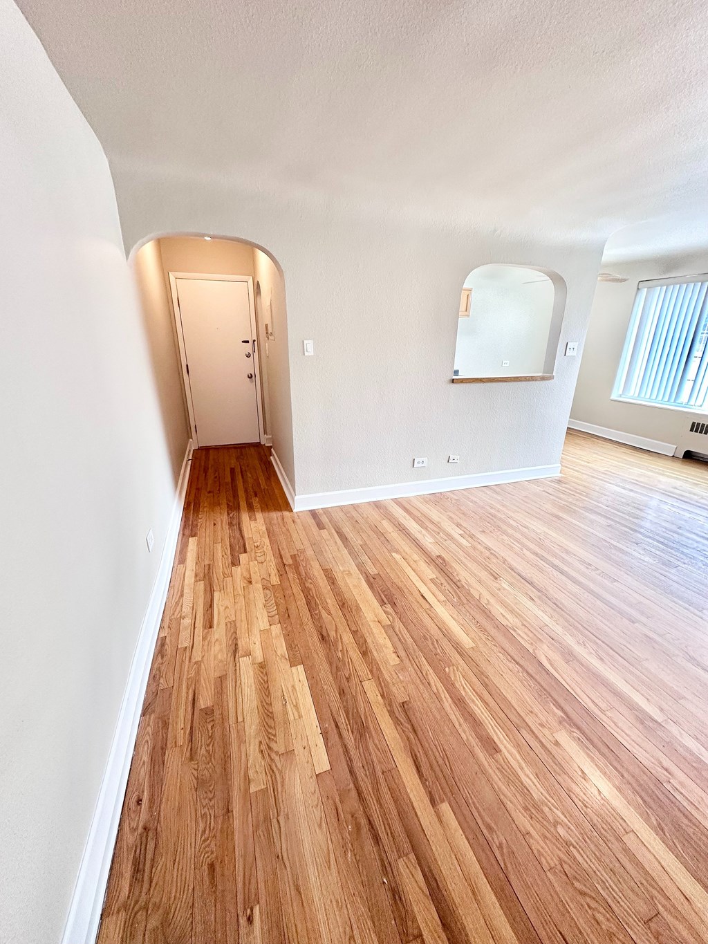 A room with wooden flooring and a white wall.