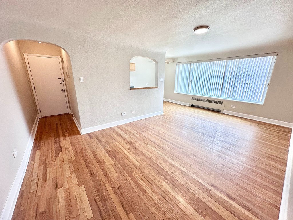A room with wooden flooring and a window with blinds.