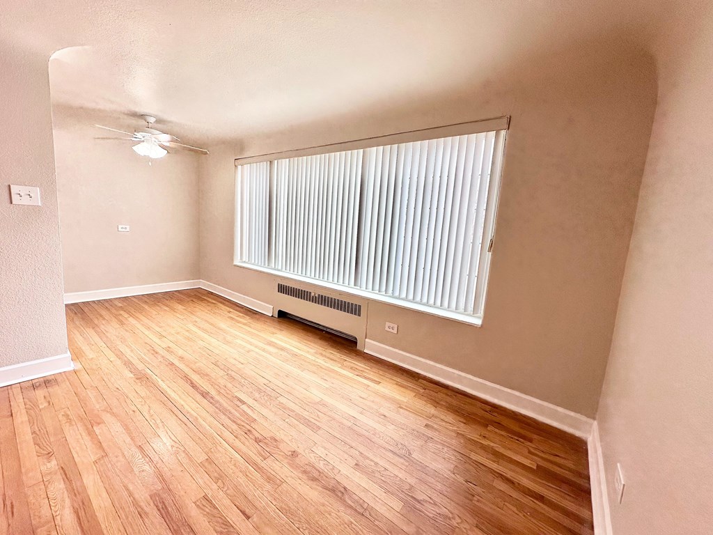 A room with wooden flooring and a window with blinds.