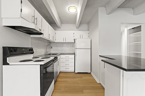 A modern kitchen with white cabinets and black countertops.