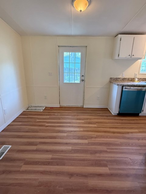 A room with a wooden floor and a door leading to a balcony.