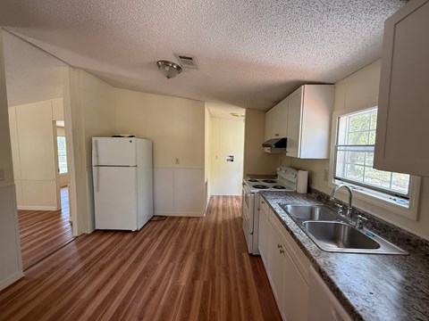 A kitchen with white appliances and wooden floors.