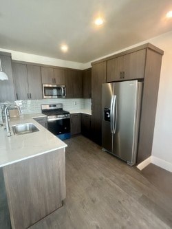 A kitchen with a refrigerator, sink, and microwave.