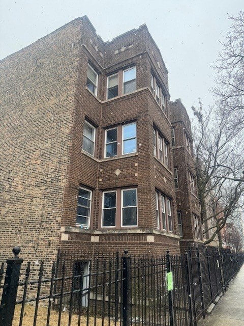 A brick building with a black fence in front.