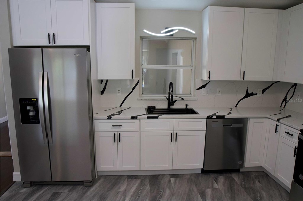A kitchen with a stainless steel refrigerator and white cabinets.
