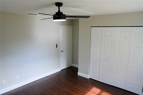 A room with a ceiling fan and a white door.