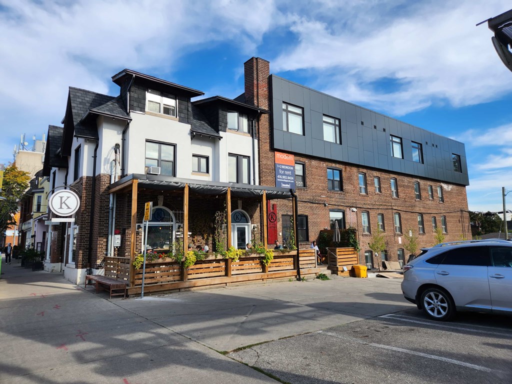A building with a white and black facade has a sign with a letter K on it.