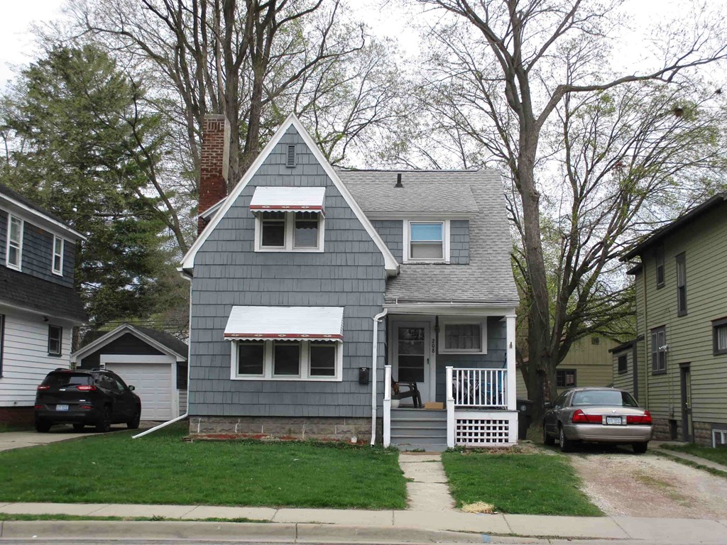 A grey house with a white roof and a red and white striped awning.