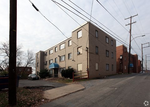 A street view of a residential area with apartment buildings and a car parked on the side of the road.