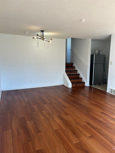 A room with wooden flooring and a staircase.