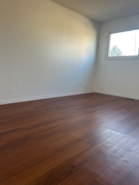 A room with wooden flooring and a window.