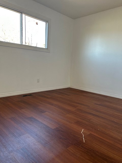 A room with a wooden floor and a window.