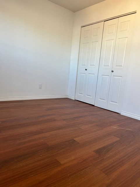 A room with a white wall and a brown floor.