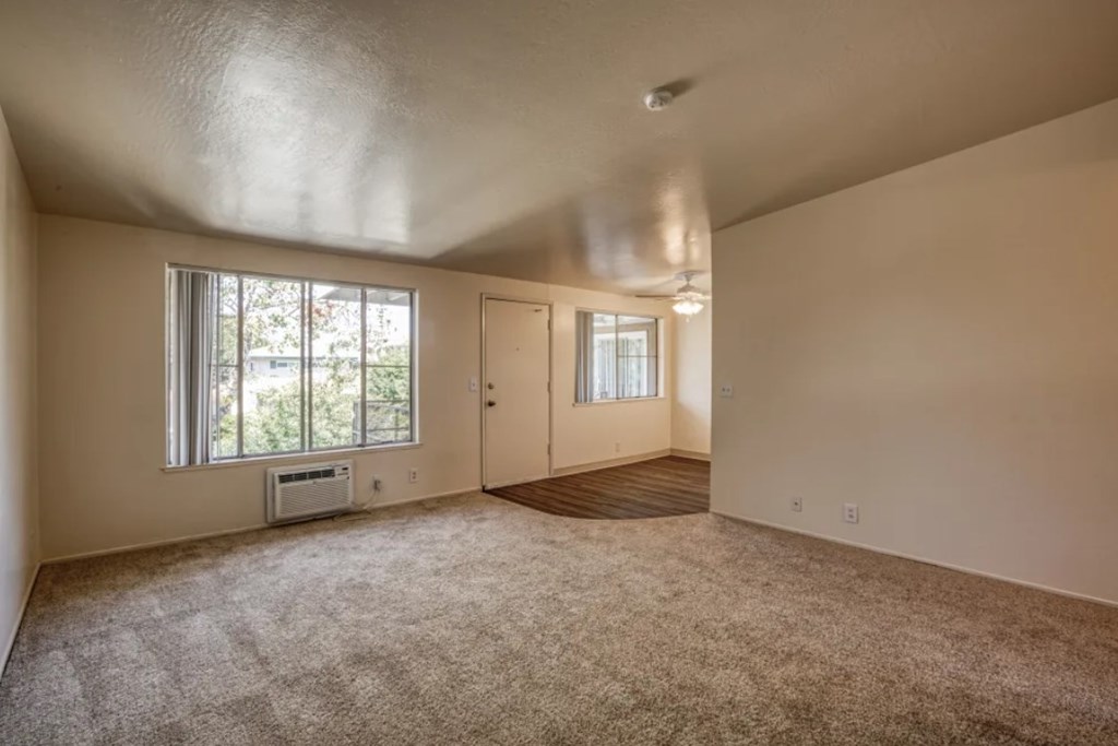 A room with a window and a door is empty and waiting to be furnished.