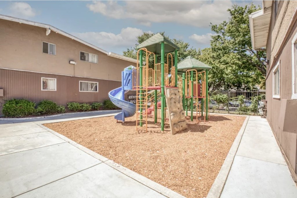 A playground with a blue slide and a green roof.