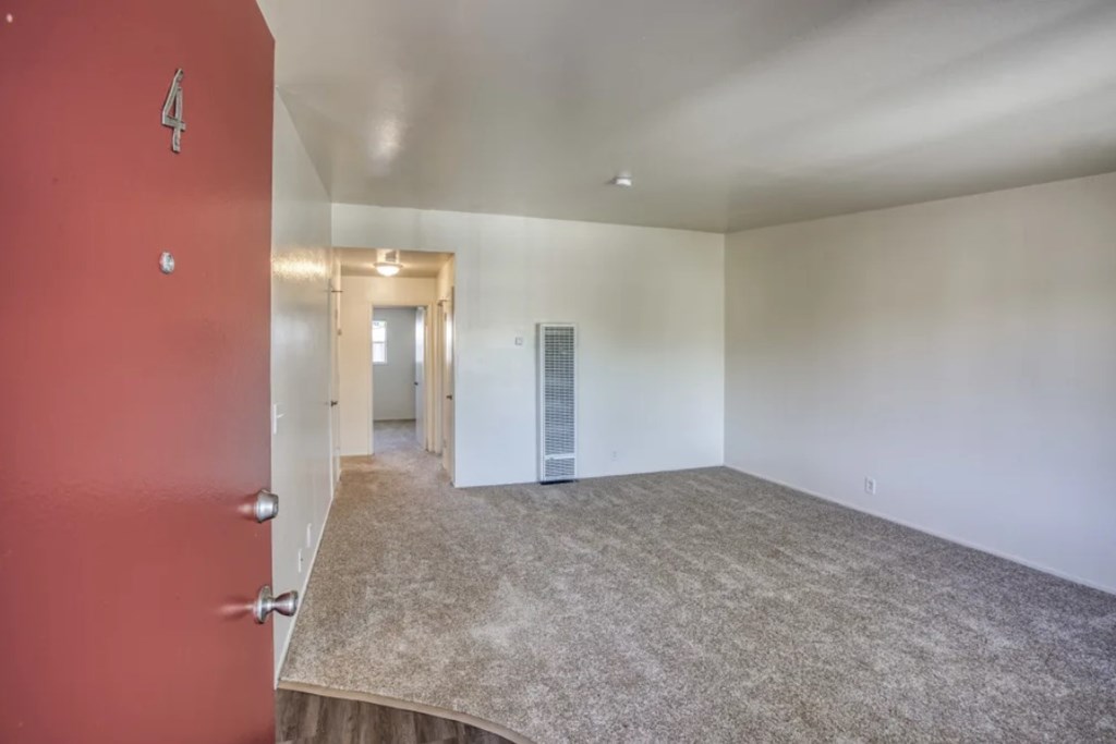 A room with a red door and carpeted floor.