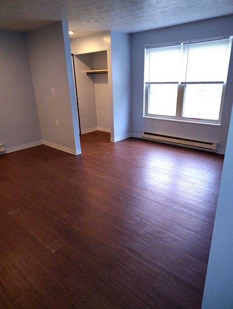 A room with wood flooring and a window.