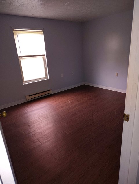 A room with a window and wooden flooring.