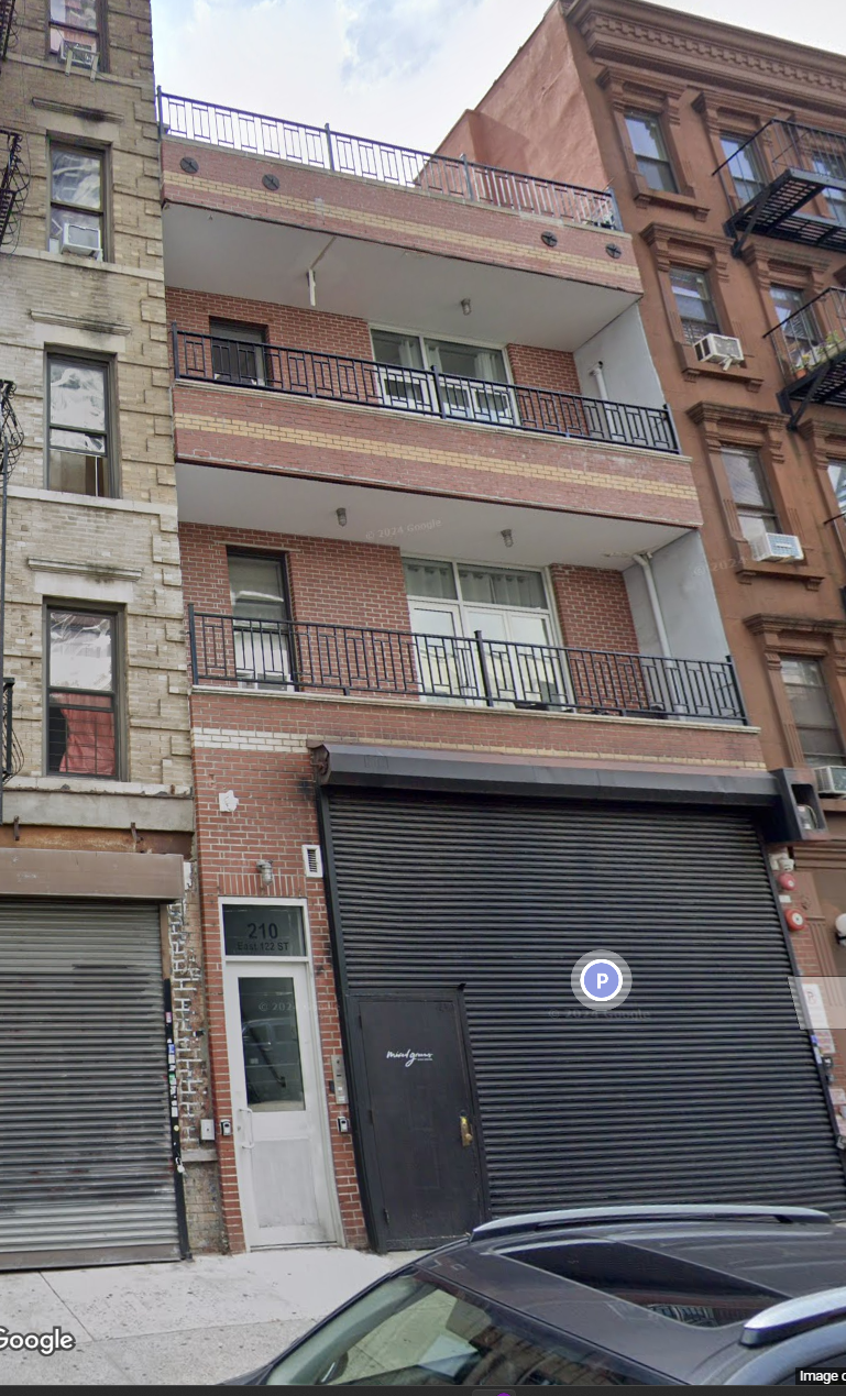 A black car is parked in front of a building with a closed black door.